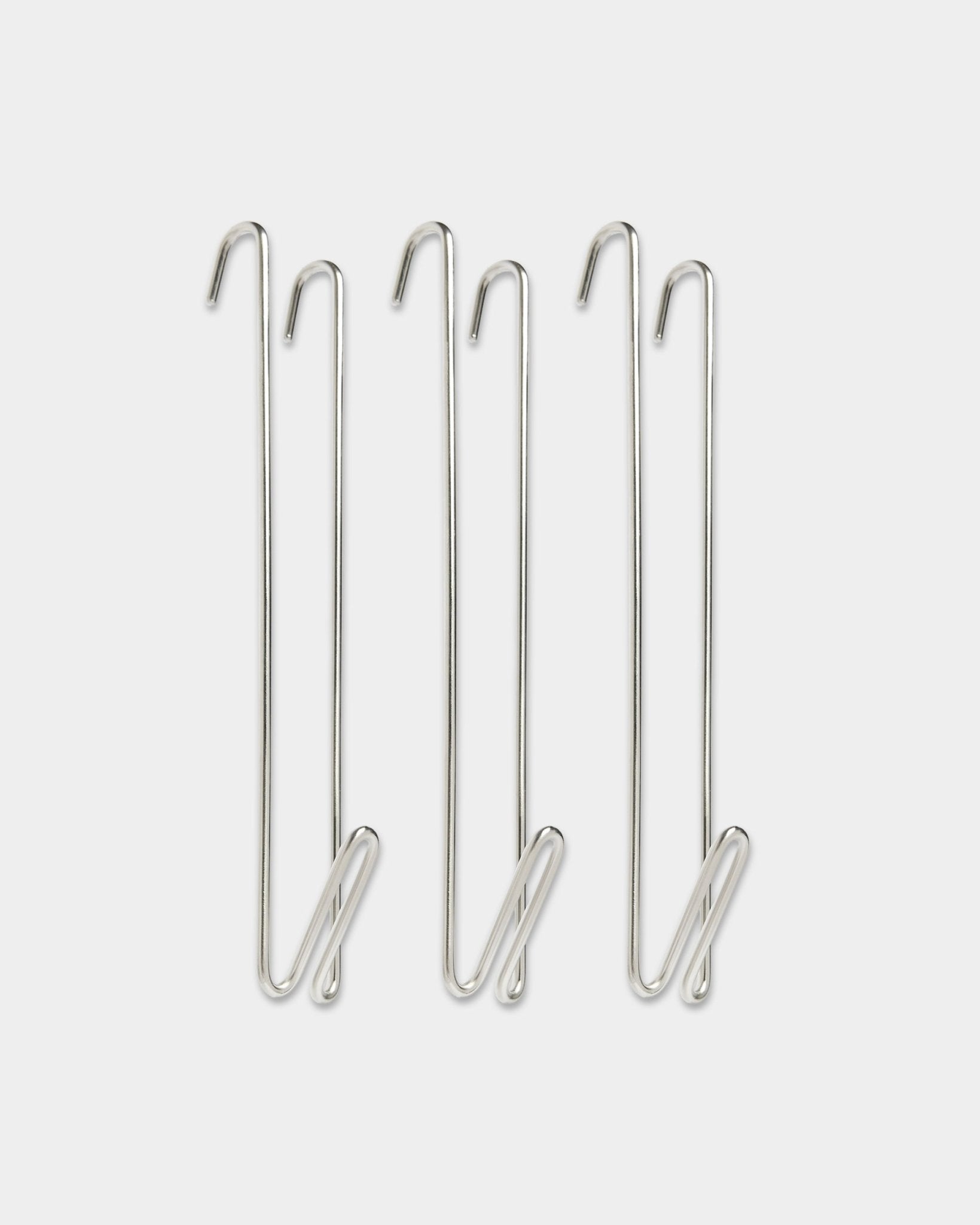 Trois rallonges de tringle de penderie à crochets métalliques WoodUpp Alva en steel inoxydable BM1, conçues pour ajouter plus d’espace de suspension à côté des panneaux acoustiques en bois.